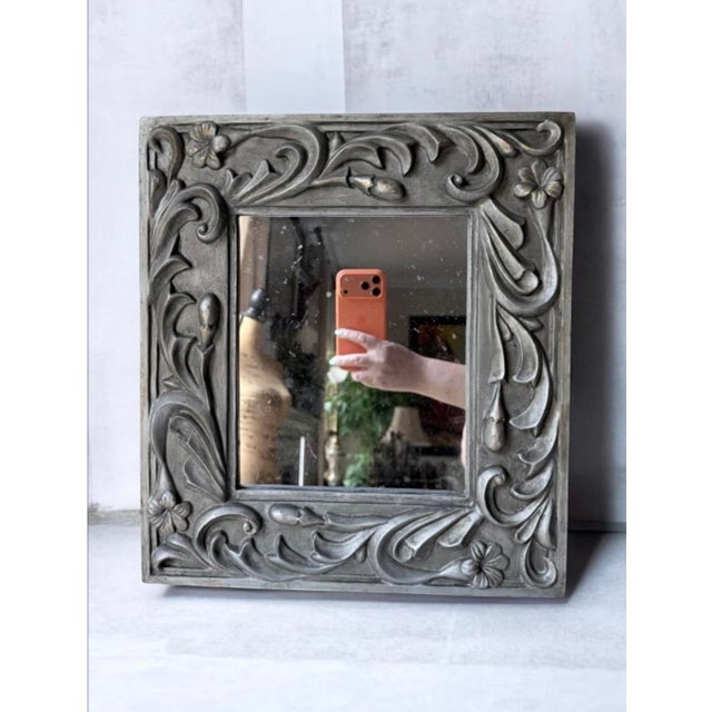 decorative floral carved square wall mirror in silver gray featuring an ornate scrollwork and blossom frame. 14.5”x13”