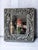 decorative floral carved square wall mirror in silver gray featuring an ornate scrollwork and blossom frame. 14.5”x13”