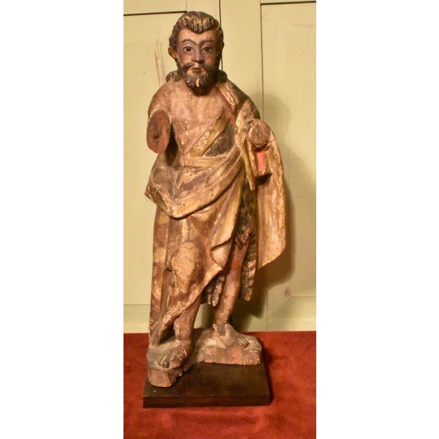 A large carved painted polychrome Santos, possibly John the Baptist. 18th century or earlier. Here he wears robes of red...
