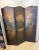 Antique painted leather screen depicting a medieval village scene and enhanced with a black iron rivet trim. Front of...