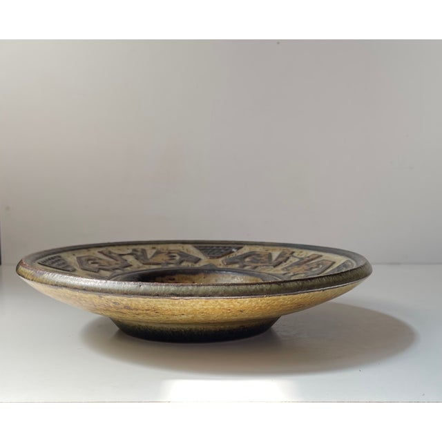 Dish or bowl by the danish ceramist Jørgen Mogensen. Stoneware with earthy brown sung glazes and with geometric relief...