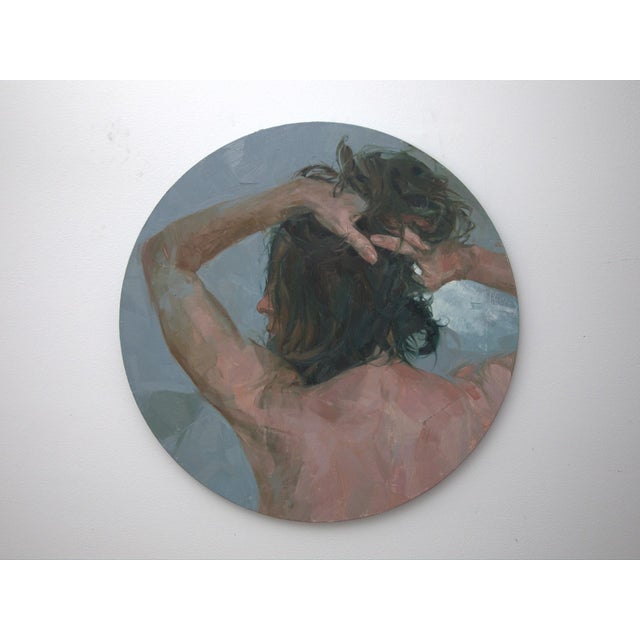 This circular oil painting captures a figure from behind, their tousled hair cascading as they pull it back, creating a...