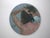 This circular oil painting captures a figure from behind, their tousled hair cascading as they pull it back, creating a...