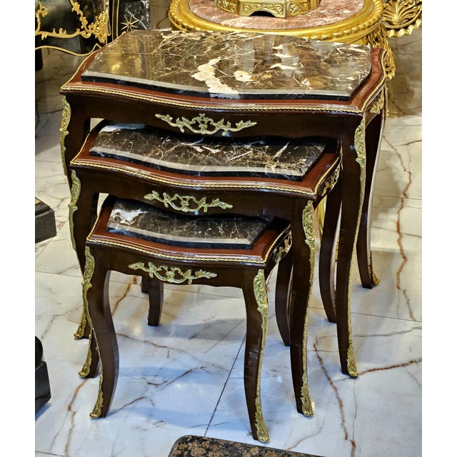 Elegant Rococo style nesting tables featuring a luxurious set of three accent tables topped with sophisticated black...