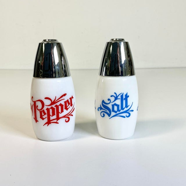 A fun set of Salt & Pepper Shakers from the late Mid-Century. They are traditional white milk glass with screw-on chrome...