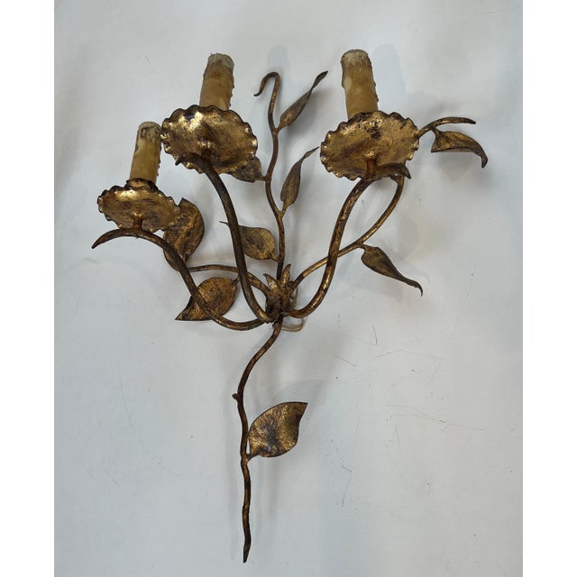 This pair of 3-light wall sconces is made of gilded metal. They are decorated with leaves. This is a French work. Circa 1970