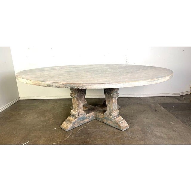 Monumental size neoclassical style round dining table with a distressed, rustic finish. Its design features intricately...