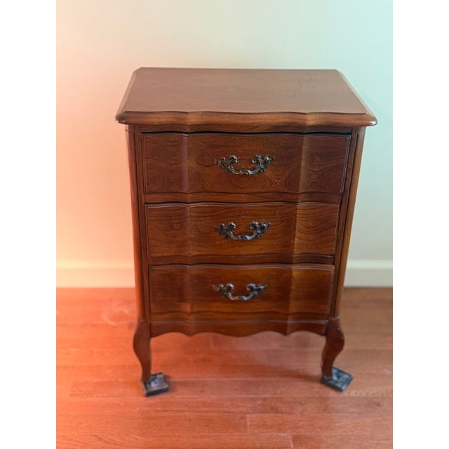 This pair of wooden nightstands features serpentine three-drawer design with carved drawer fronts., cabriole legs, and...