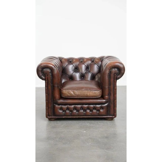 Offered this classic and luxurious dark brown English cowhide leather chesterfield armchair with decorative rivets. This...