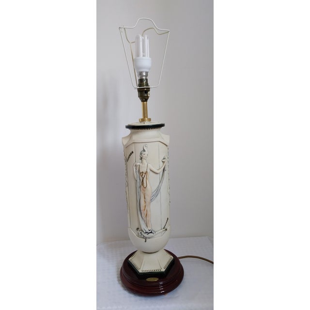 This is a unique, large Florence table lamp. It has a porcelain body on a wooden base, with a female figure on one side...
