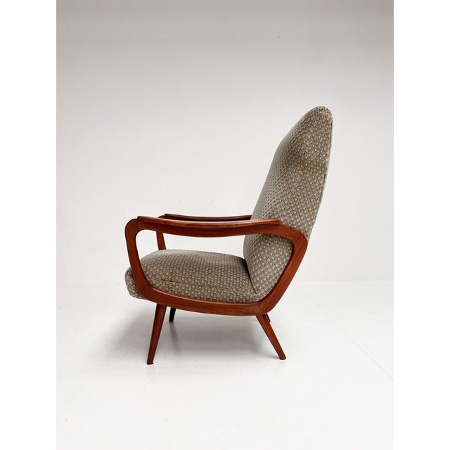 Great vintage armchair from the 1960s. The organically shaped wooden armrests immediately catch the eye. The lounge chair...