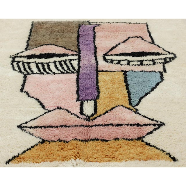 Artistic hand-knotted wool rug showcasing an abstract face design in Dusty Rose, Sky Blue, Taupe, and Mustard Yellow on an...