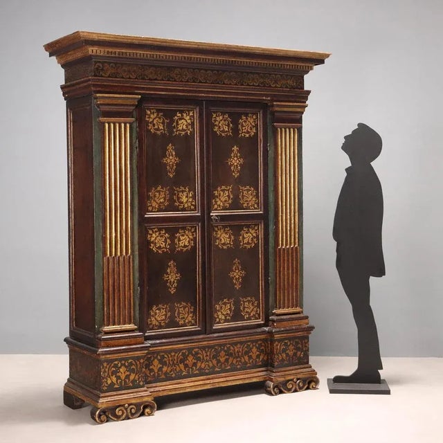 Mannerist wardrobe in lacquered walnut, with walnut parts, painted parts and gold leaf gilded parts. Front with pair of...