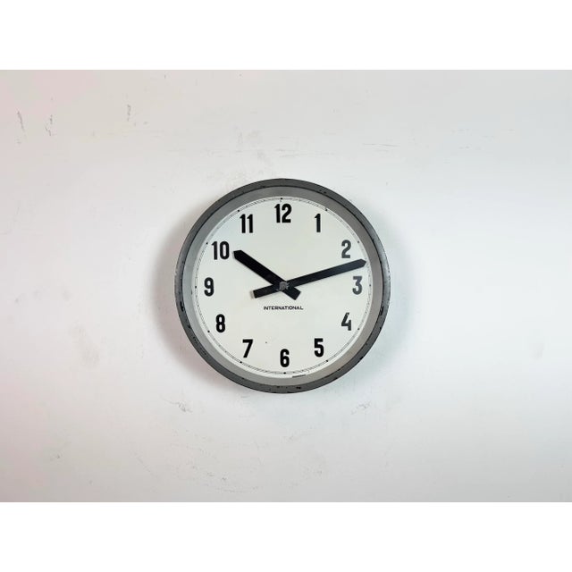 This wall clock was produced by International in Germany during the 1950s. It features a grey metal frame, an iron dial,...
