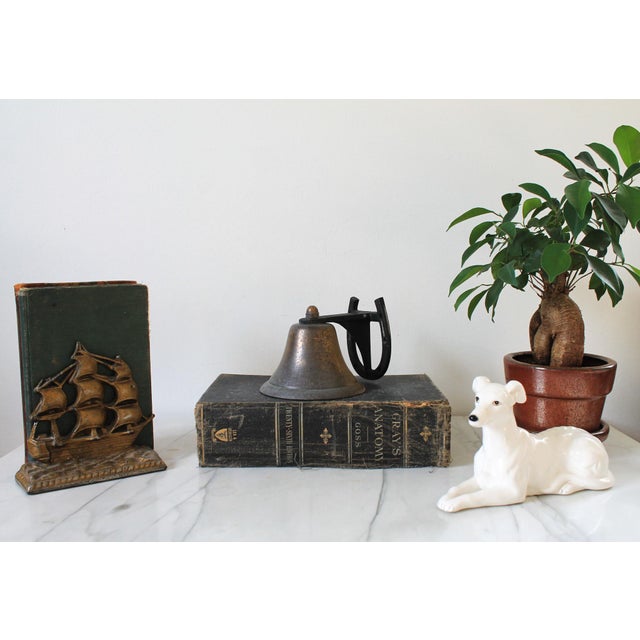 Vintage western style wall mounted metal dinner bell with horse shoe motif. No makers mark. Age wear to brass plated...