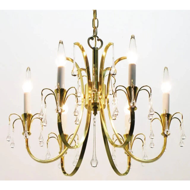 Modernist crystal chandelier with six C-curve arms and brass end cups. Raindrop crystals hang from every arm, with long...