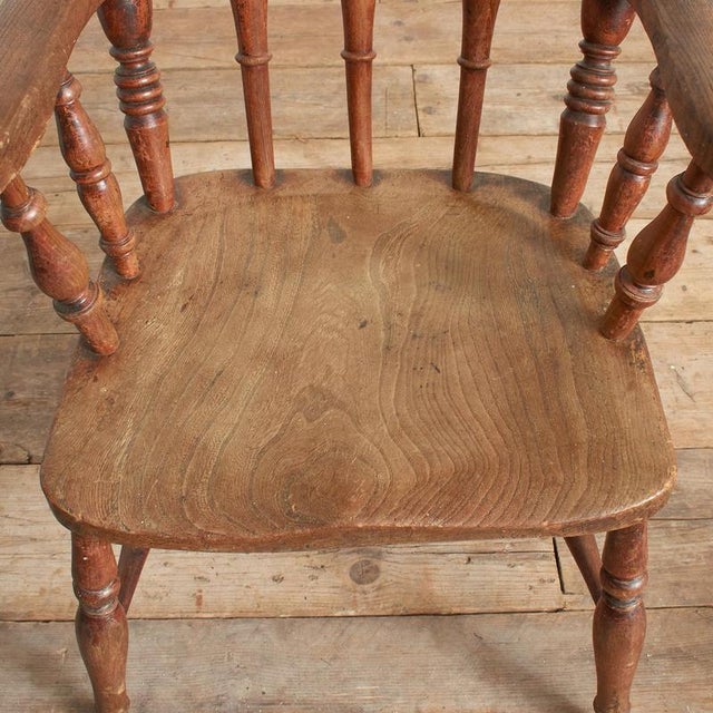 A charming windsor spindle kitchen carver chair with solid elm seat, raised on turned ash supports with h framed...