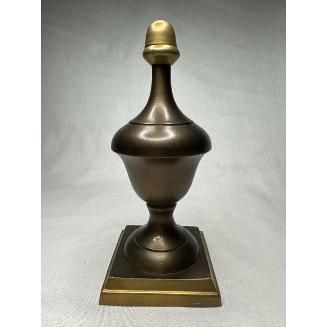 There’s a soft satin sheen on this mixed metal bronze and brass finish finial in bronze. Its' style leans toward a...