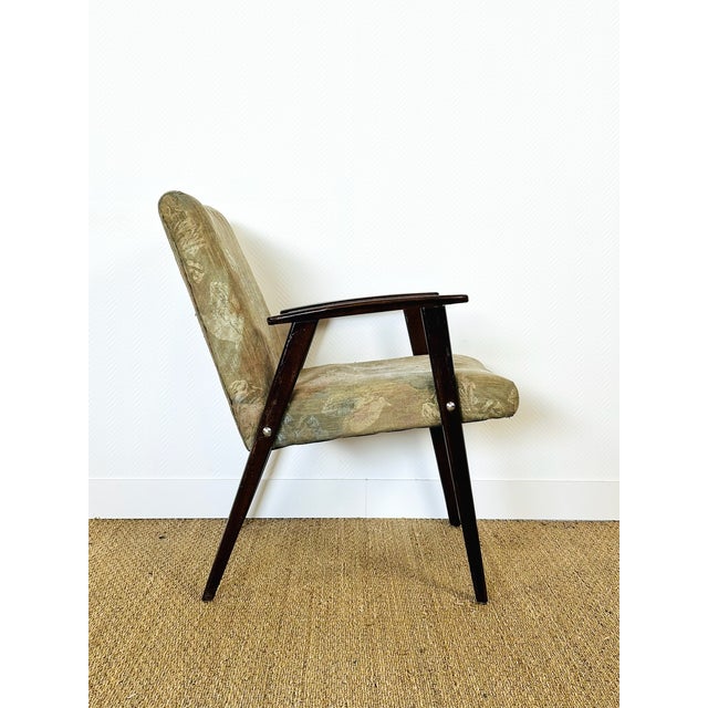 Vintage armchair with a scandinavian design typical of the mid-20th century. its dark-stained solid wood frame offers...