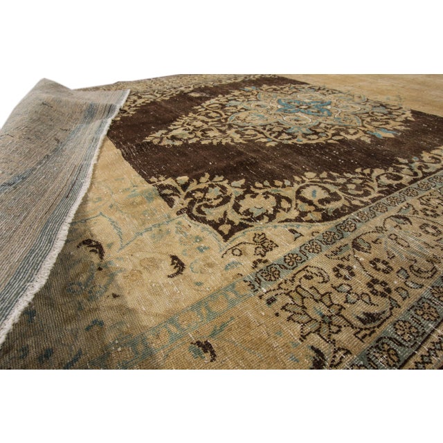 Beautiful vintage Persian Tabriz hand-knotted wool rug with a brown field. This piece has beige and teal accents in an...