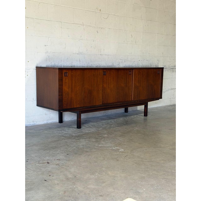 This exceptional low credenza showcases striking symmetrical grain patterns across its entire front profile. Elegant...