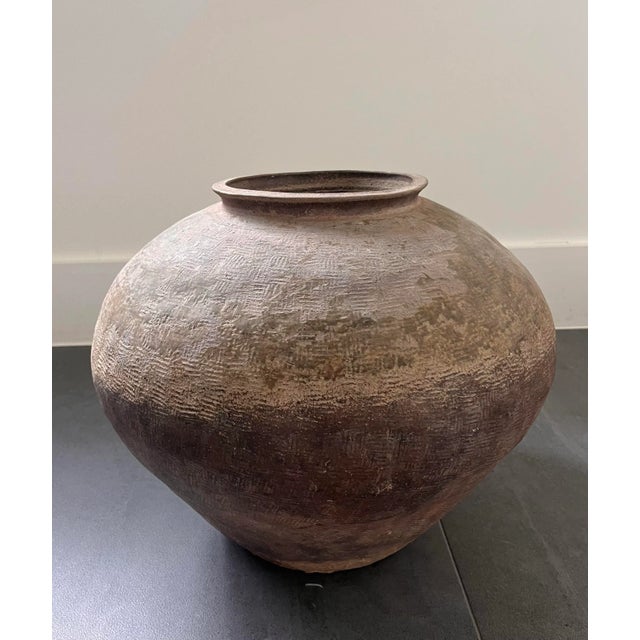 Chinese Banshan style unglazed earthenware jar with a tapered body and textured sides.