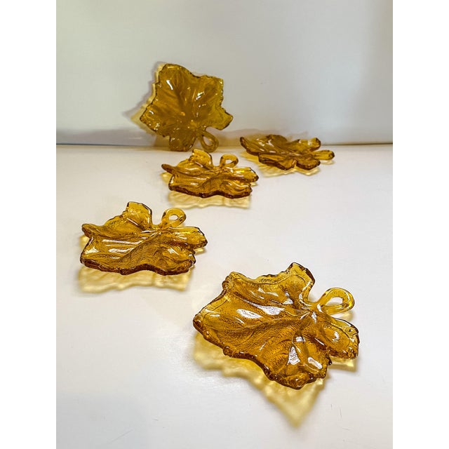 A set of five textured amber glass trinket dishes with looped handles in a whimsical maple leaf shape. Provides a nice...