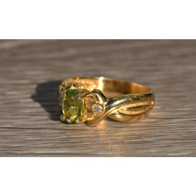 The Teleri Ladies 14K Peridot and Diamond Twist Ring. This ring is crafted in 14 karat yellow gold and centers on an oval...