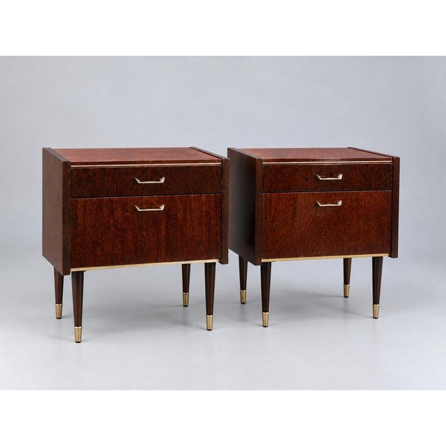 Set of 2 vintage design nightstands with brass details. A stylish set of two vintage design nightstands featuring a warm,...