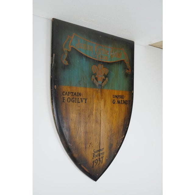 This shield shaped wooden piece displays Junior Carlton Cricket Club, Captain Fogilvy, Umpire G. Mundy, Summer Fixtures...