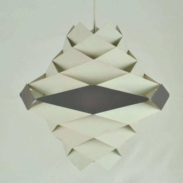 Symfoni lamp in white and dark grey-black painted metal diamonds assembled to an origami style lampshades is designed by...