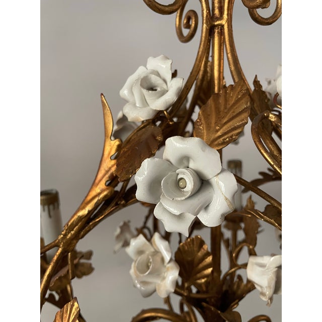 This vintage gilt tole chandelier from the mid-century features an elegant botanical design adorned with delicate white...