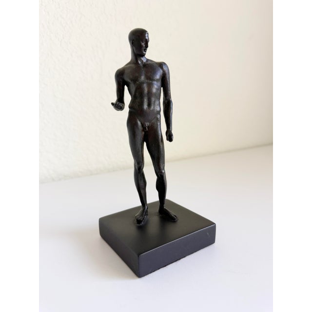 A Metropolitan Museum of Art reproduction of a standing male Greco-Roman athlete sculpture. The classical male figure is...