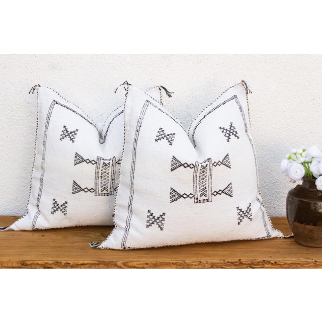 Sold as a matching pair, these handcrafted Moroccan cactus silk pillows feature a central bowtie medallion and crossed-X...