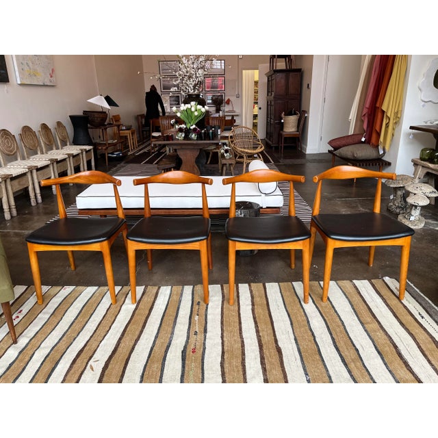 Set of four Wegner cowhorn-style chairs. Black leather or vinyl seats.