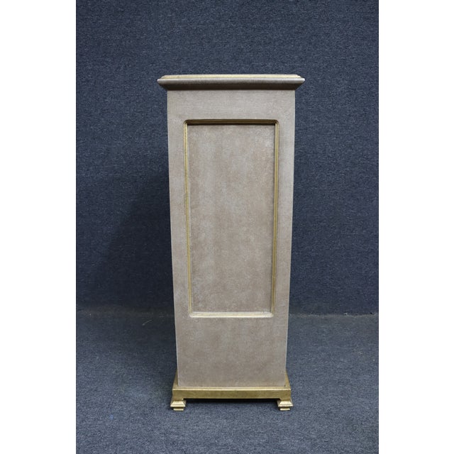 Painted pedestal stand with a simple, clean form and subtle gold accents. Features a neutral faux finish with recessed...