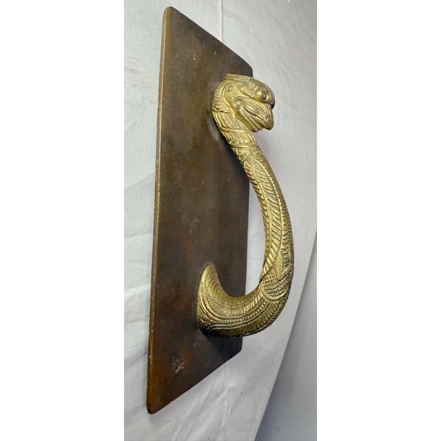 This antique door handle is a beautifully crafted piece of hardware featuring ornate tooled brass with a fixed griffin and...
