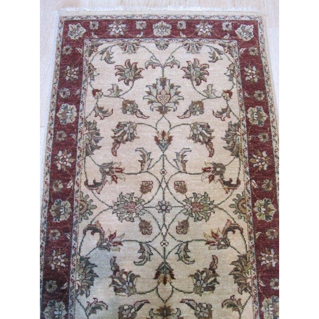 This ivory, beige, cream, and white runner is a hand knotted pile rug crafted from natural wool. It represents the classic...
