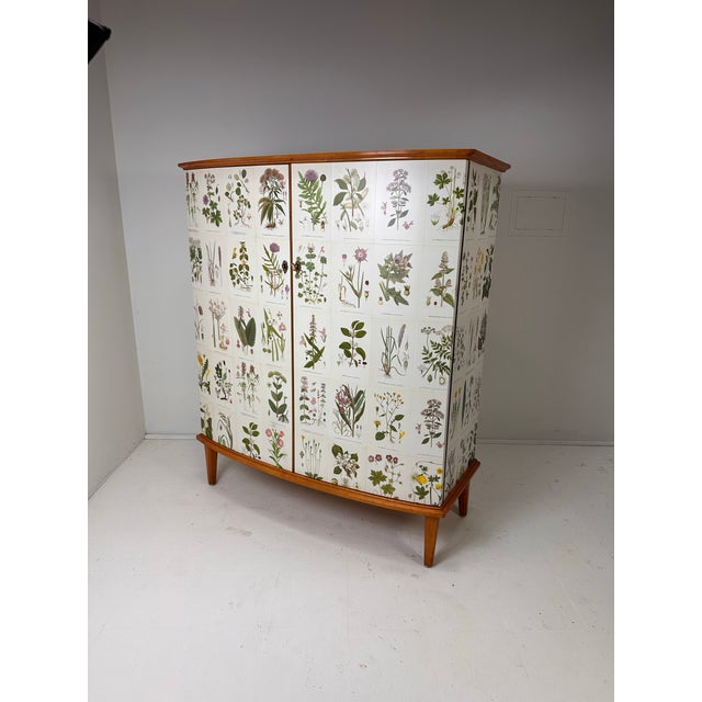 1950’s curved front Swedish cabinet later papered with illustrations by C.A. Lindman book Nordens Flora. Cabinet consists...