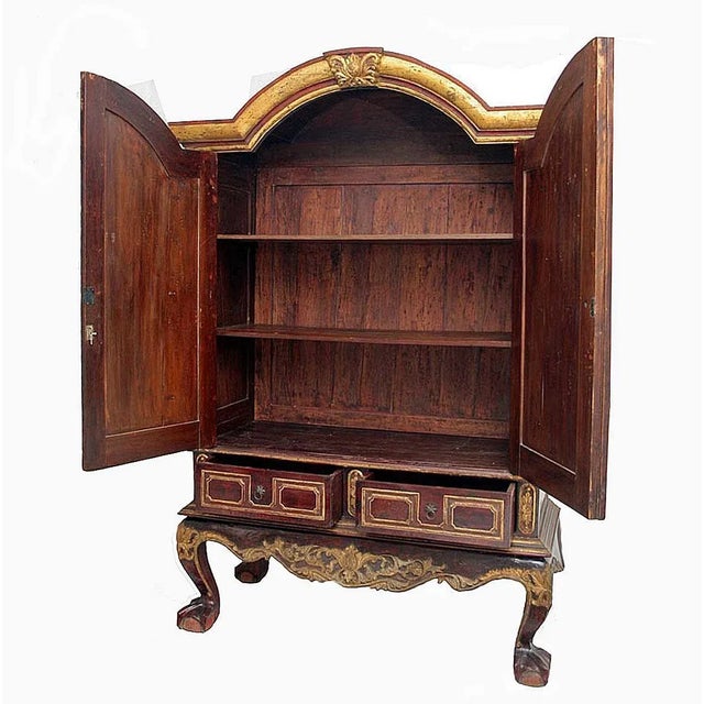 A large polychromed wood cabinet with two doors and shelves from Central Java, Indonesia, circa 1930. Hand-carved accents,...