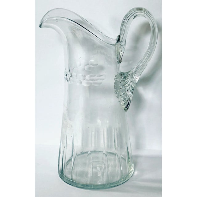 This lovely blown glass pitcher has a ribbed handle that prevents slipping and fluting radiating up from the base along...