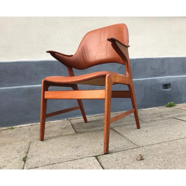 Solid teak armchair or lounge chair recently upholstered in tanned brown aniline leather. The 'nails' armrests are made...