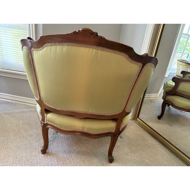Elegant vintage Louis XV style bergère chair featuring a beautifully carved wood frame, cabriole legs, and tufted...