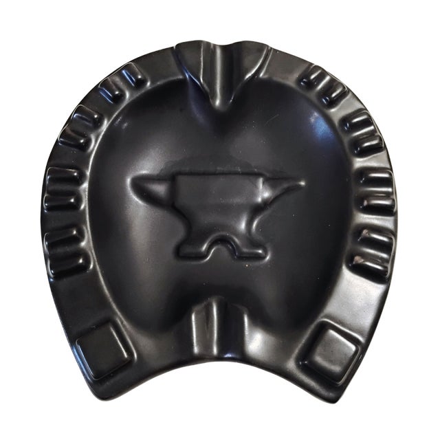 This classic mid-century Royal Haeger ceramic ashtray features a bold horseshoe design centered by a raised blacksmith's...