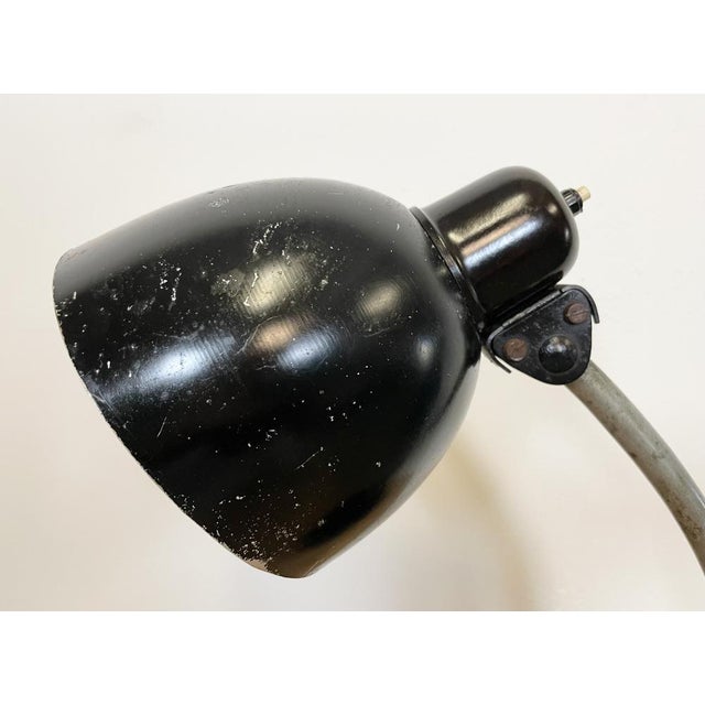 This black industrial workshop desk lamp was made in former Czechoslovakia during the 1950s. The lamp has an adjustable...