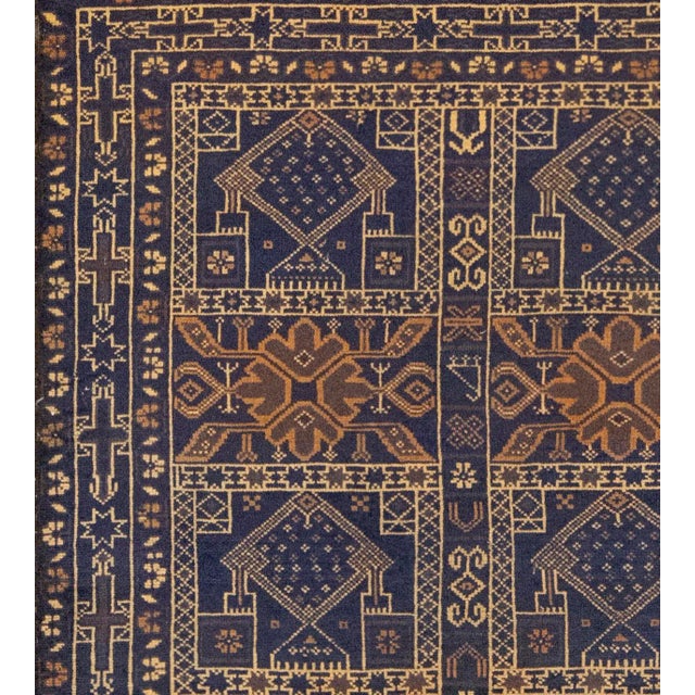 This small hand-woven Baluch rug has a central field with two columns of five shaded blue panels containing alternating...