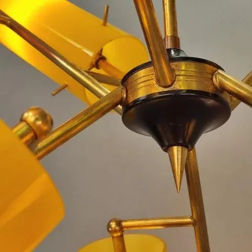 A classic Italian chandelier from the 1950s, attributed to Stilnovo. Brass structure with cylindrical yellow and red glass...