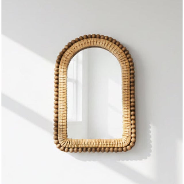 Arched beveled mirror with woven rattan frame surrounded with a perimeter of round, brown wooden beads. Condition: very...