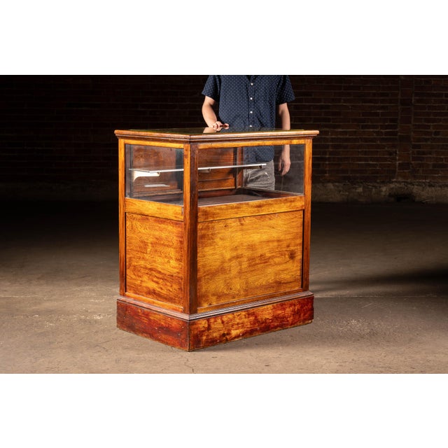 Oak barber shop display cabinet featuring a glazed upper showcase with fixed side glass, removable glass display shelf,...