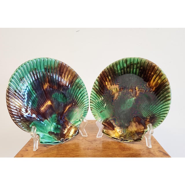 From Wedgwood, a set of two English majolica scallop shell shaped, mottled tortoiseshell glazed plates. Each plate shows a...